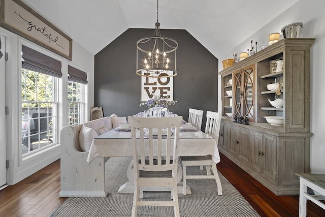 dining space featuring visible vents, vaulted ceiling, an inviting chandelier, and wood finished floors