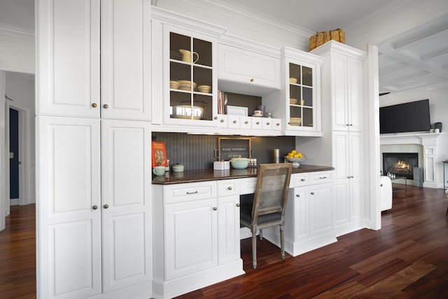 bar featuring dark wood-style floors, a glass covered fireplace, crown molding, and built in study area