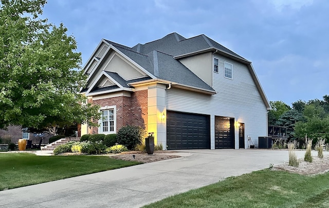 view of front of property with central air condition unit, brick siding, concrete driveway, roof with shingles, and a front yard