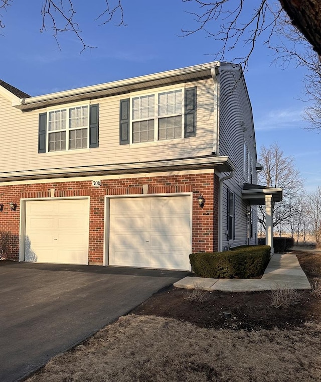 view of property exterior featuring aphalt driveway, brick siding, and an attached garage