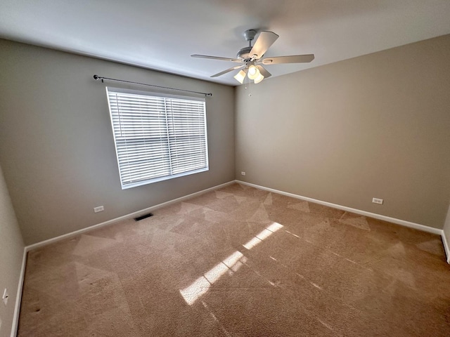 carpeted spare room with a ceiling fan, visible vents, and baseboards