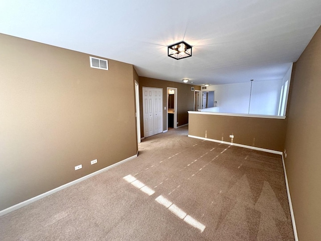 carpeted empty room featuring baseboards and visible vents