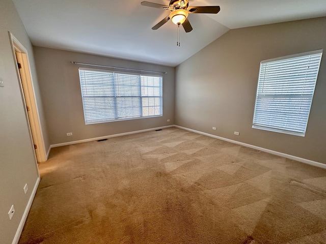 spare room featuring vaulted ceiling, baseboards, a ceiling fan, and light colored carpet