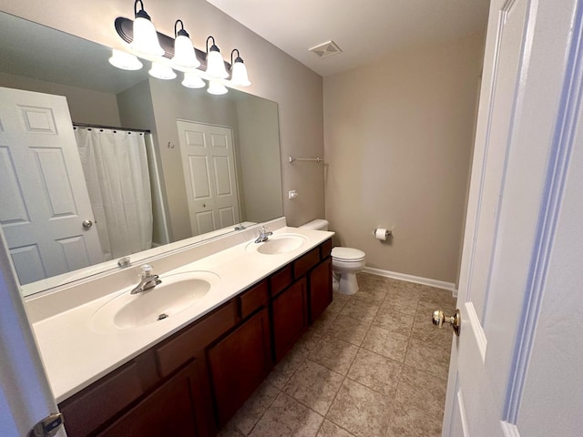 bathroom with toilet, a sink, visible vents, baseboards, and double vanity