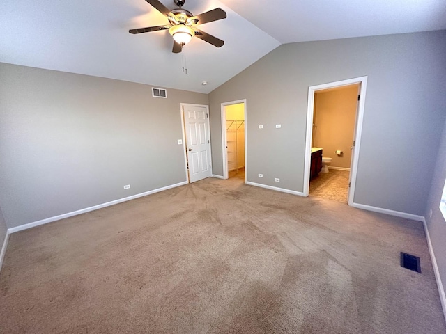 unfurnished bedroom featuring lofted ceiling, baseboards, visible vents, and a walk in closet