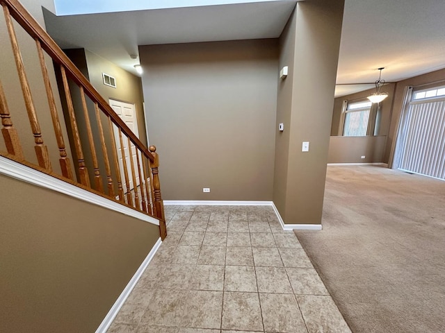 foyer with baseboards, visible vents, tile patterned floors, stairs, and carpet flooring