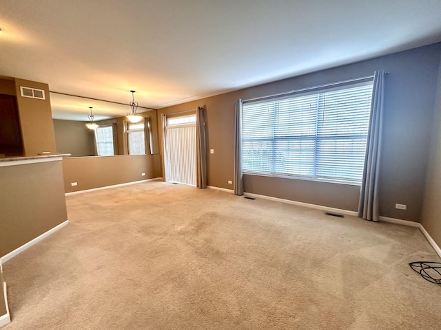 empty room with baseboards, visible vents, and carpet flooring