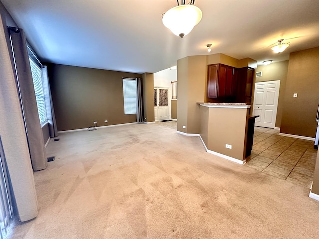 unfurnished living room featuring light carpet, baseboards, and a wealth of natural light