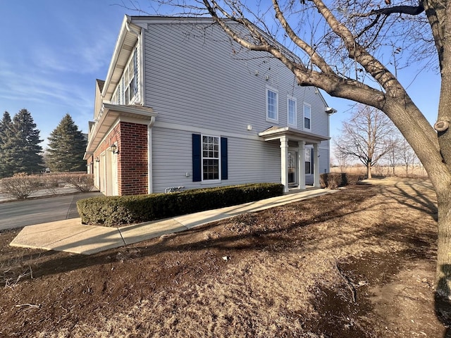 view of home's exterior with a garage, driveway, and brick siding