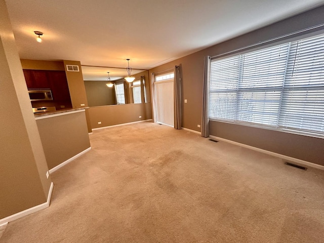 unfurnished living room with light carpet, visible vents, and baseboards