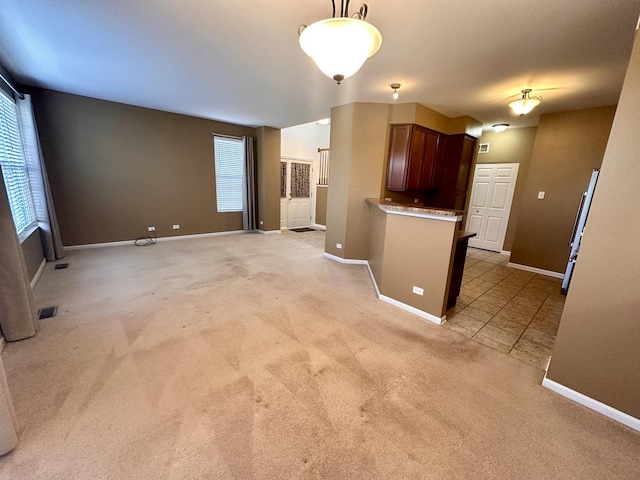 interior space with baseboards, plenty of natural light, decorative light fixtures, and light colored carpet