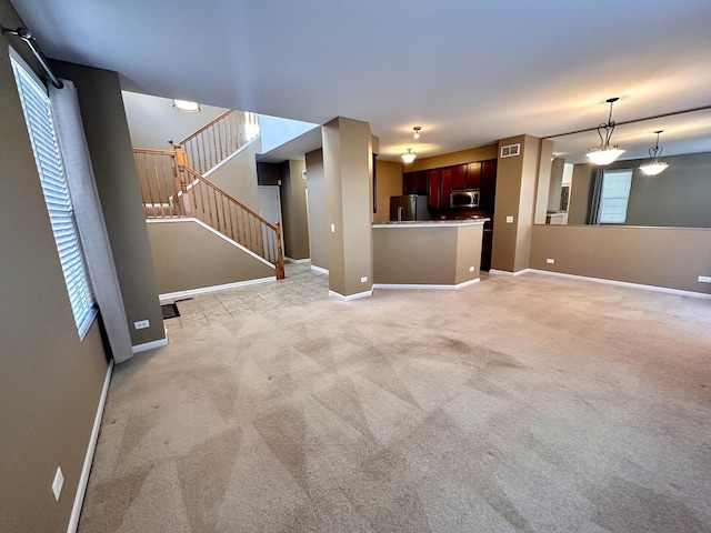 unfurnished living room featuring light carpet, baseboards, stairs, and visible vents