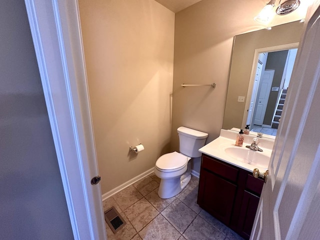 half bath with toilet, vanity, visible vents, baseboards, and tile patterned floors