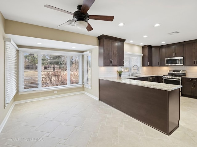 kitchen with visible vents, light stone counters, stainless steel appliances, dark brown cabinetry, and decorative backsplash