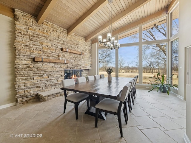 dining space with a stone fireplace, an inviting chandelier, beamed ceiling, and high vaulted ceiling