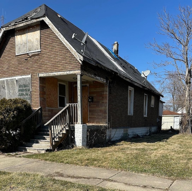 view of front of house featuring covered porch, brick siding, and a chimney