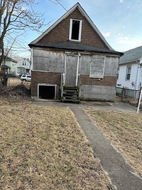 rear view of house featuring entry steps, fence, and brick siding