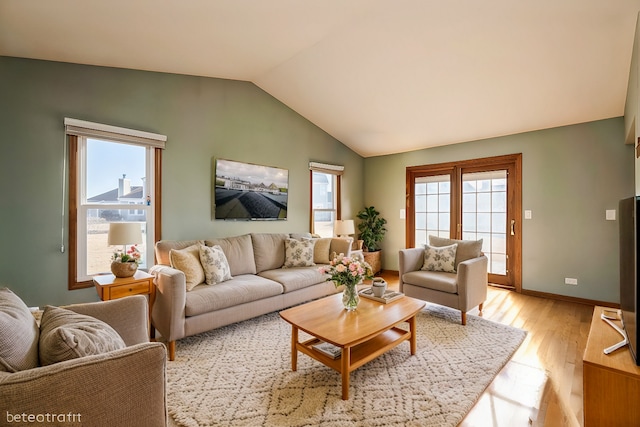 living area with light wood finished floors, baseboards, and lofted ceiling