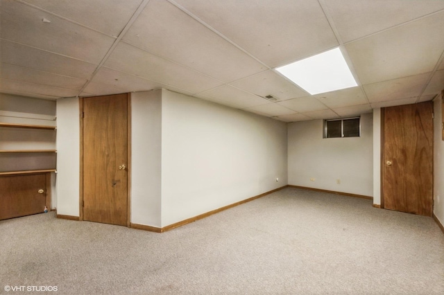 finished below grade area featuring a drop ceiling, carpet floors, baseboards, and visible vents