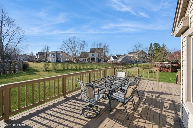 deck featuring a residential view, a lawn, and outdoor dining space