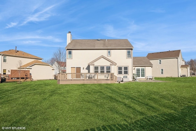 rear view of house featuring a deck, a chimney, and a yard