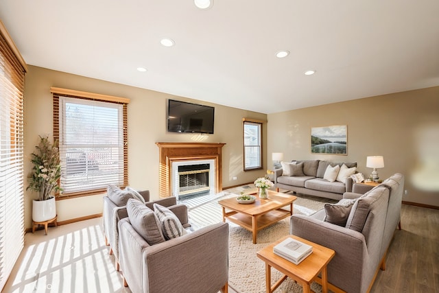 living area featuring a glass covered fireplace, recessed lighting, and baseboards