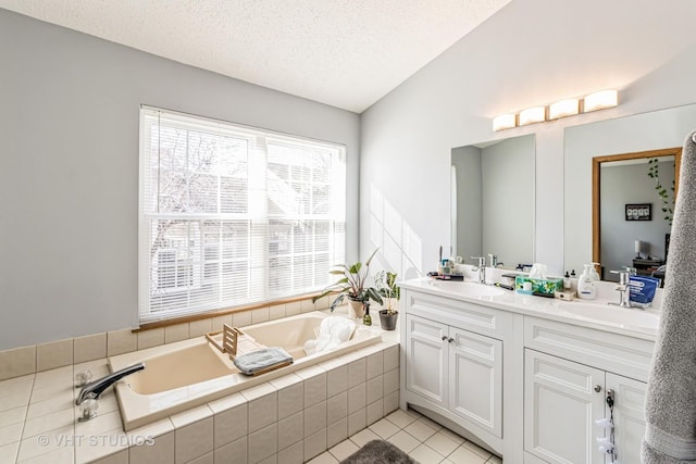 bathroom with a textured ceiling, a garden tub, double vanity, and a sink