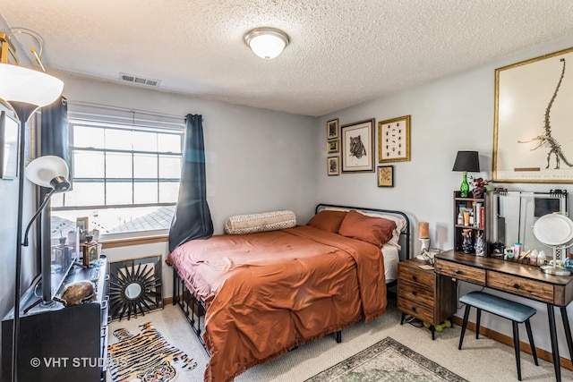 bedroom with baseboards, light colored carpet, visible vents, and a textured ceiling