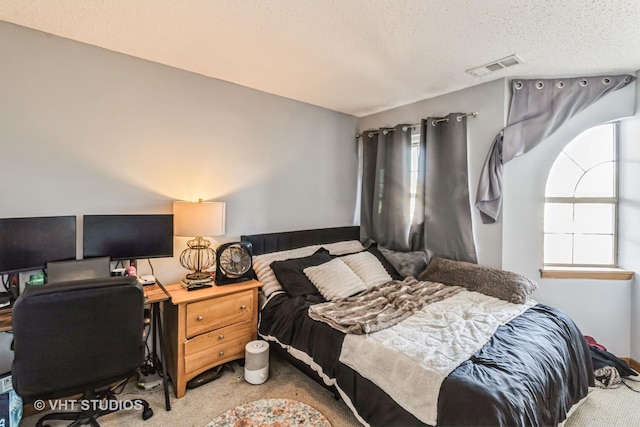 carpeted bedroom with visible vents and a textured ceiling