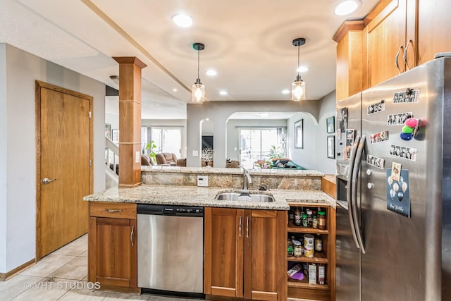 kitchen featuring a sink, open floor plan, stainless steel appliances, light tile patterned flooring, and brown cabinetry