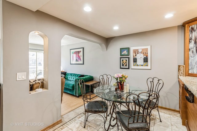 dining space with recessed lighting, baseboards, and arched walkways