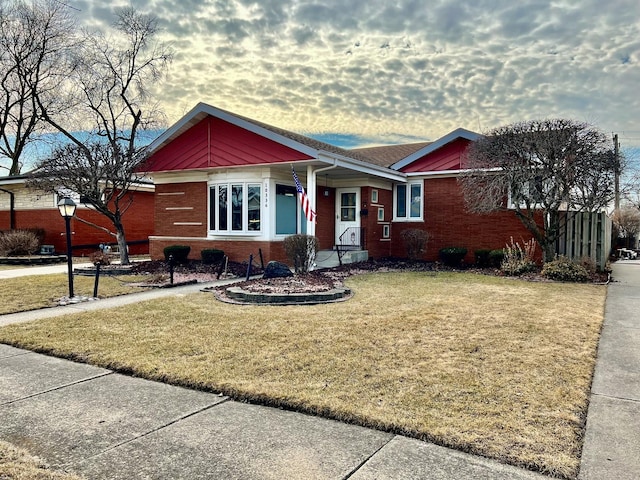 view of front of home featuring brick siding and a front lawn