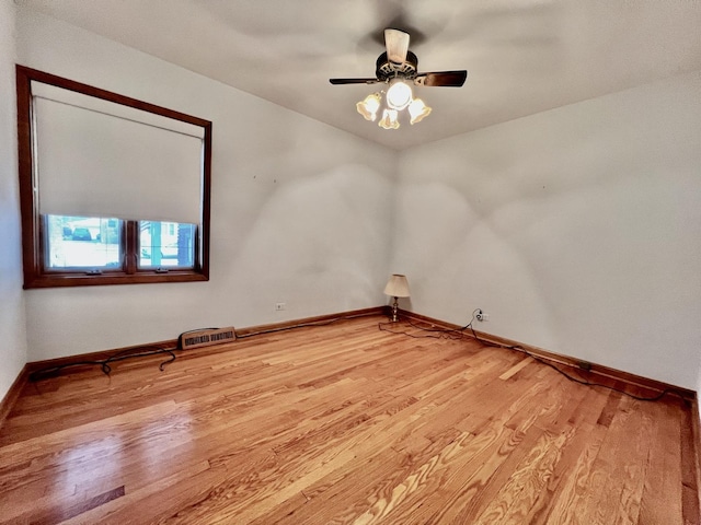 empty room with wood finished floors, visible vents, and baseboards