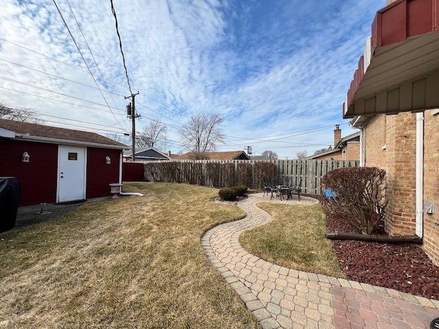 view of yard with an outbuilding, a patio area, and fence