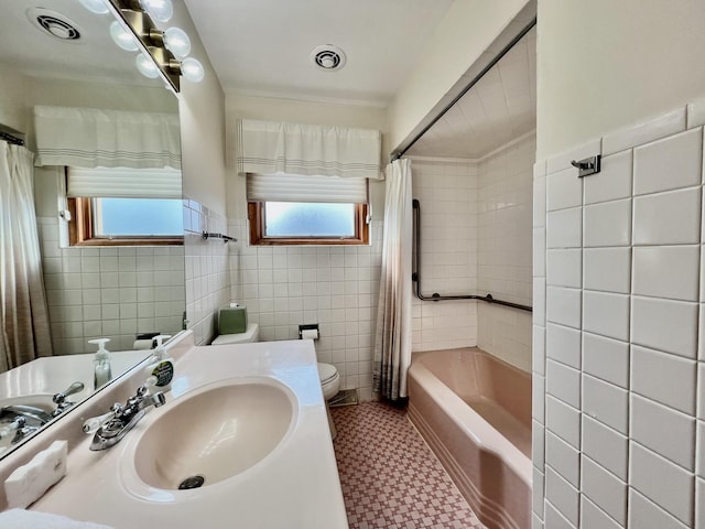 bathroom with a wealth of natural light, visible vents, tile walls, and toilet