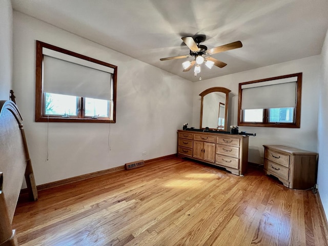 unfurnished bedroom featuring a ceiling fan, light wood-style flooring, visible vents, and baseboards