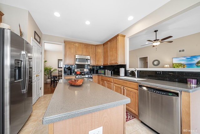 kitchen featuring a center island, visible vents, backsplash, appliances with stainless steel finishes, and a sink