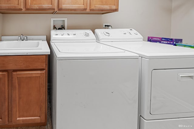 laundry area with washing machine and dryer, a sink, and cabinet space