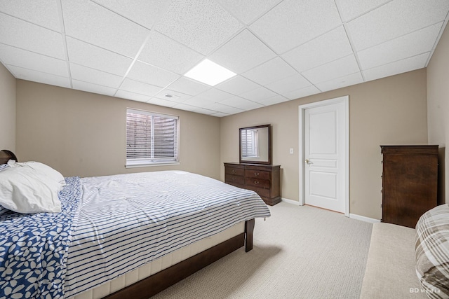 bedroom featuring a paneled ceiling, light colored carpet, visible vents, and baseboards