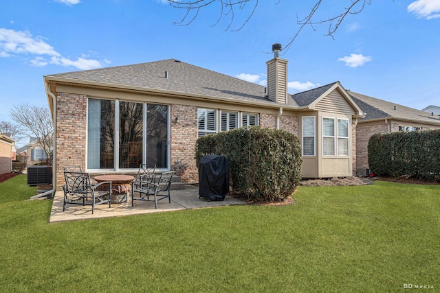 back of house featuring a chimney, a yard, a patio area, central AC, and brick siding