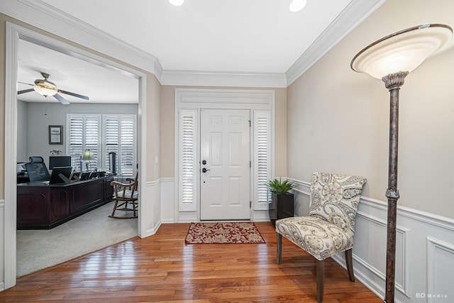 foyer featuring ornamental molding, a wainscoted wall, hardwood / wood-style floors, and a ceiling fan