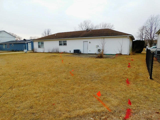 back of property featuring fence, a lawn, and central air condition unit