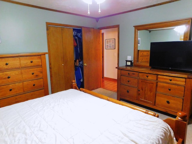 bedroom with a closet, crown molding, and wood finished floors