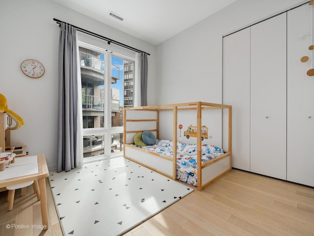 bedroom with a closet, visible vents, and wood finished floors