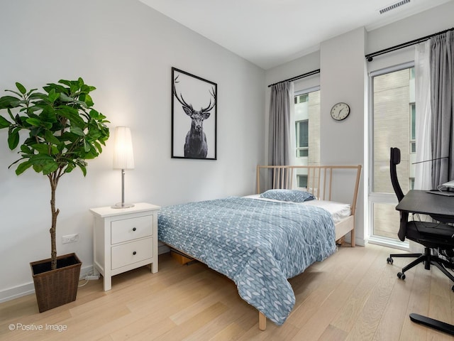 bedroom with light wood-type flooring, baseboards, visible vents, and access to exterior