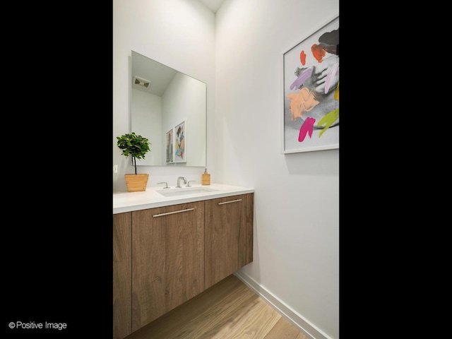 bathroom with visible vents, vanity, baseboards, and wood finished floors