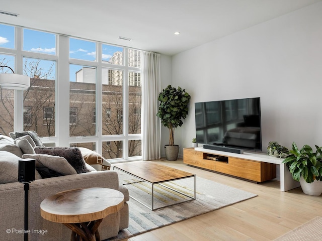 living room with a wall of windows, visible vents, wood finished floors, and recessed lighting