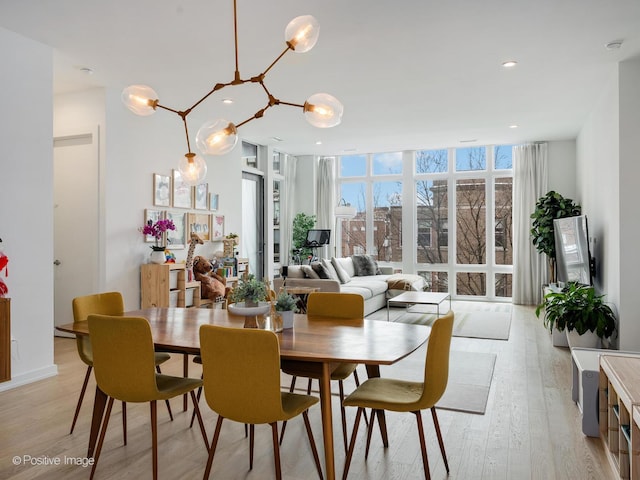 dining room with recessed lighting, light wood-type flooring, and a wall of windows