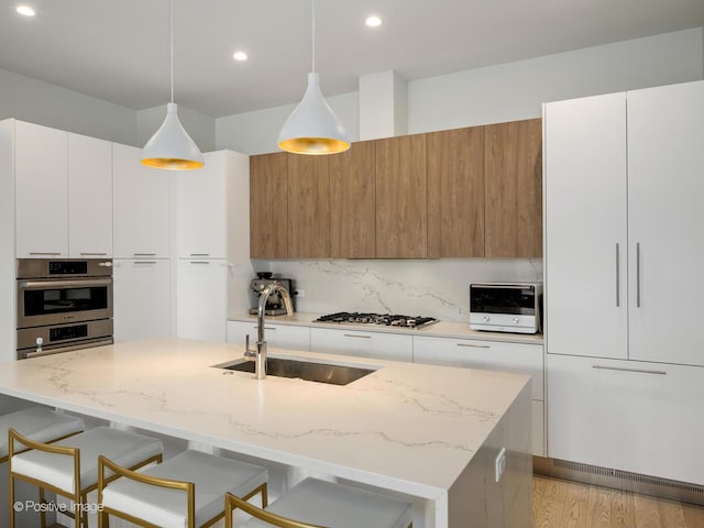 kitchen featuring modern cabinets, a sink, a kitchen breakfast bar, gas cooktop, and backsplash