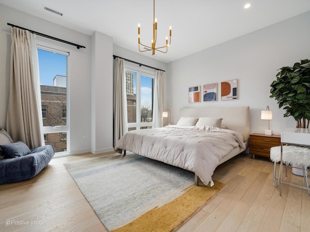 bedroom with light wood finished floors, visible vents, an inviting chandelier, and access to outside